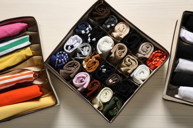 Organizers with folded clothes on light wooden table, flat lay