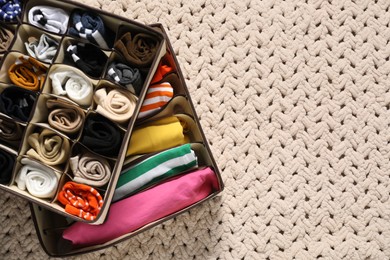 Photo of Organizers with folded clothes on beige blanket, top view. Space for text