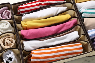 Organizers with folded clothes on table, above view