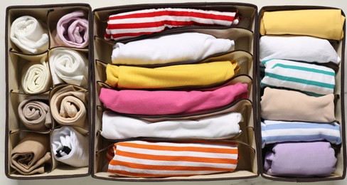 Photo of Organizers with folded clothes on table, flat lay