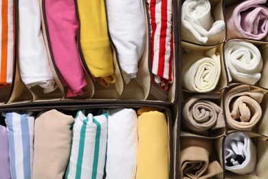 Organizers with folded clothes as background, top view