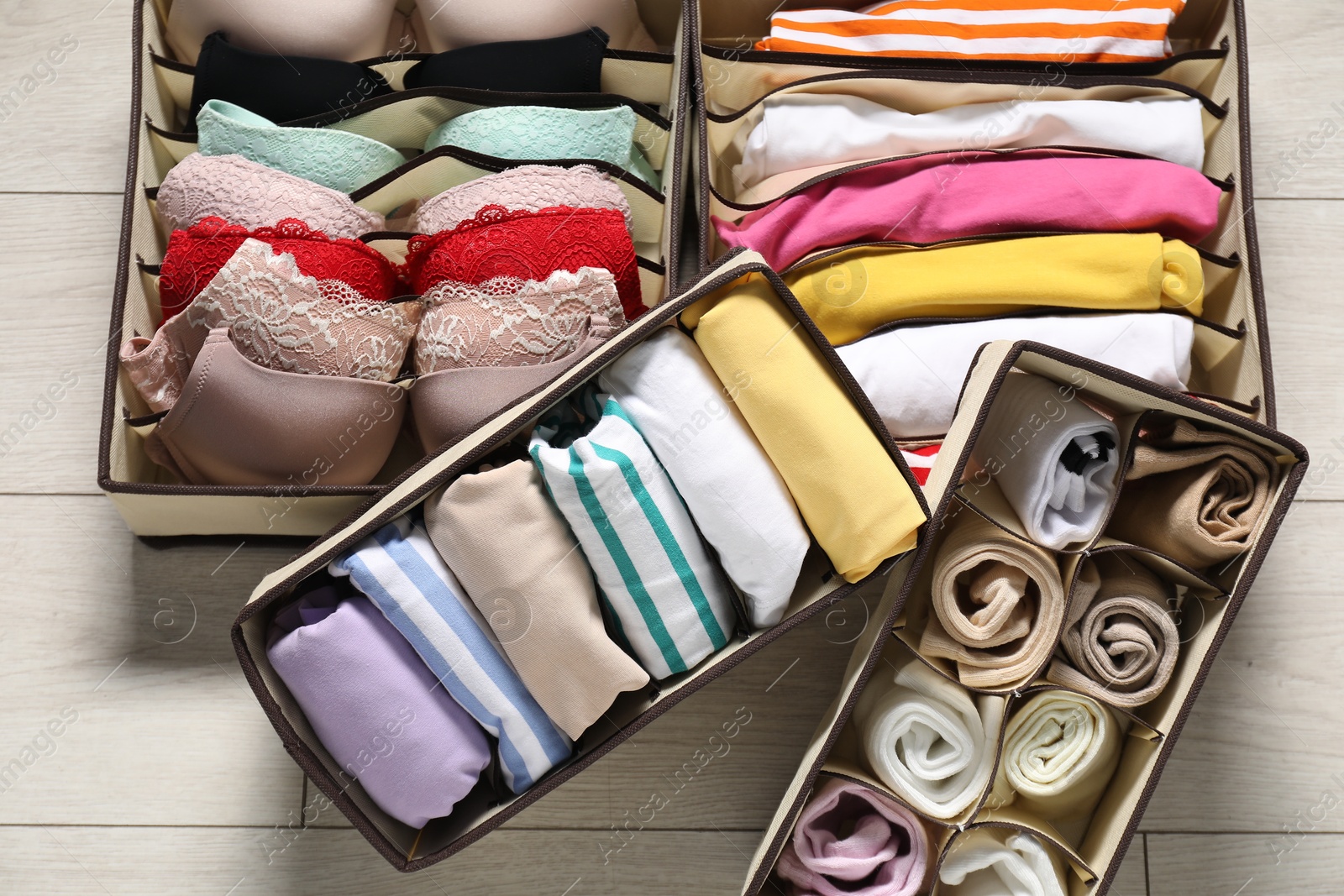 Photo of Organizers with folded clothes and underwear on wooden floor, above view