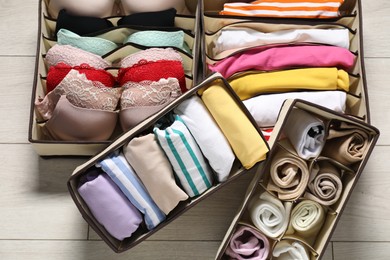 Organizers with folded clothes and underwear on wooden floor, above view