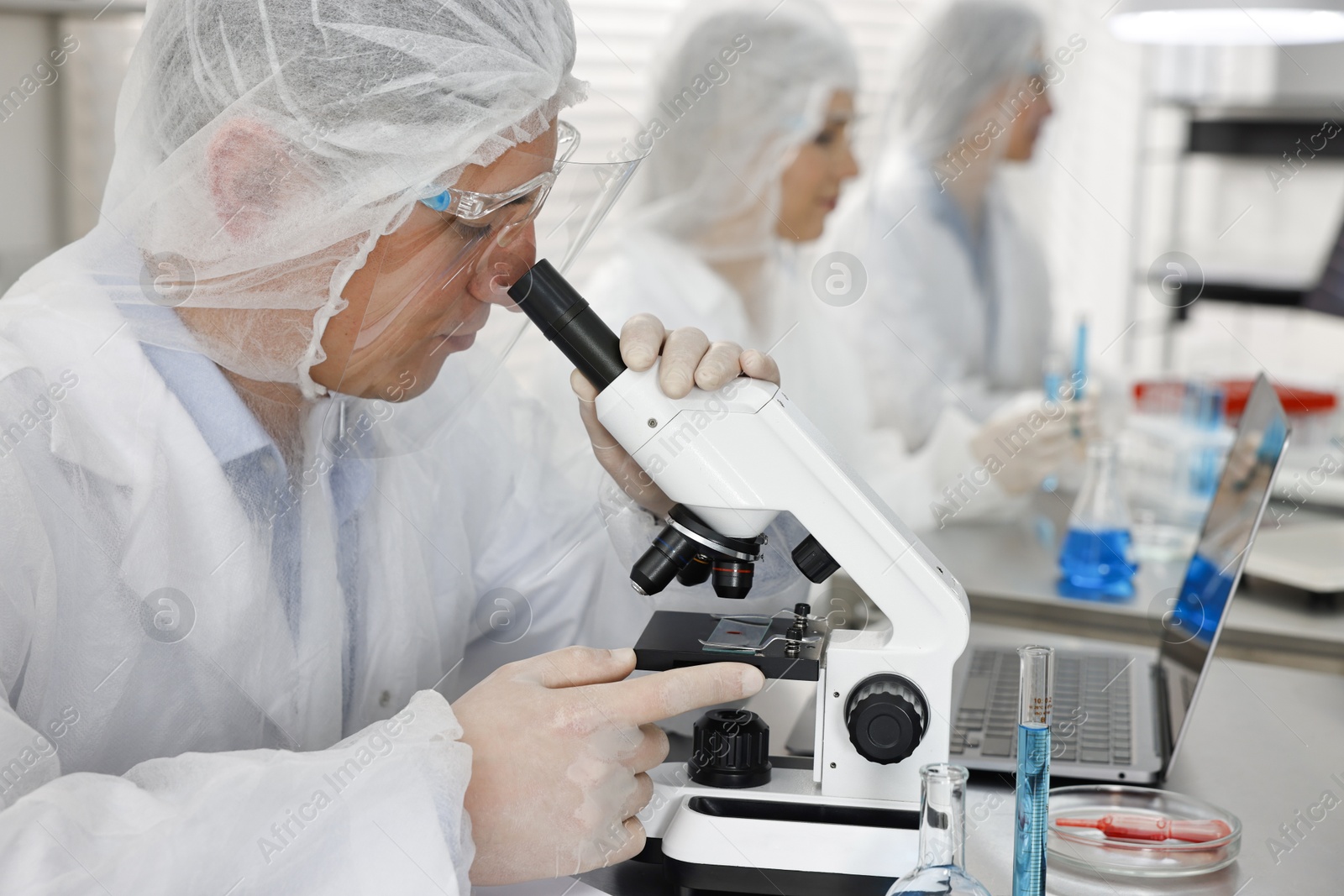 Photo of Scientist working with microscope at table in laboratory