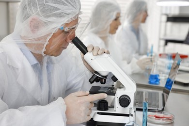 Scientist working with microscope at table in laboratory