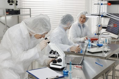 Photo of Scientist working with microscope at table in laboratory