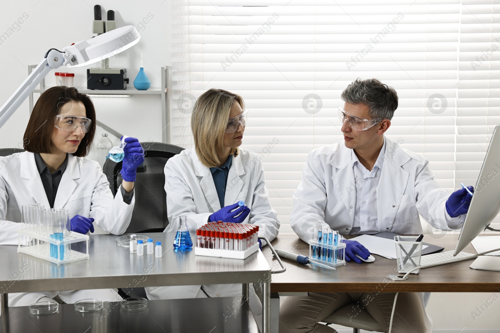 Photo of Scientists working with computer and samples at table in laboratory