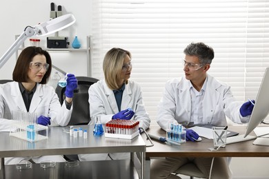 Scientists working with computer and samples at table in laboratory