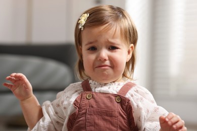 Cute little baby girl crying at home