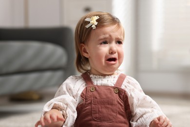 Cute little baby girl crying at home