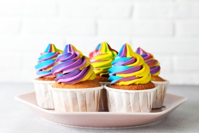 Photo of Tasty cupcakes with colorful cream on light grey table, closeup