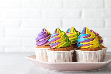 Tasty cupcakes with colorful cream on light grey table, closeup