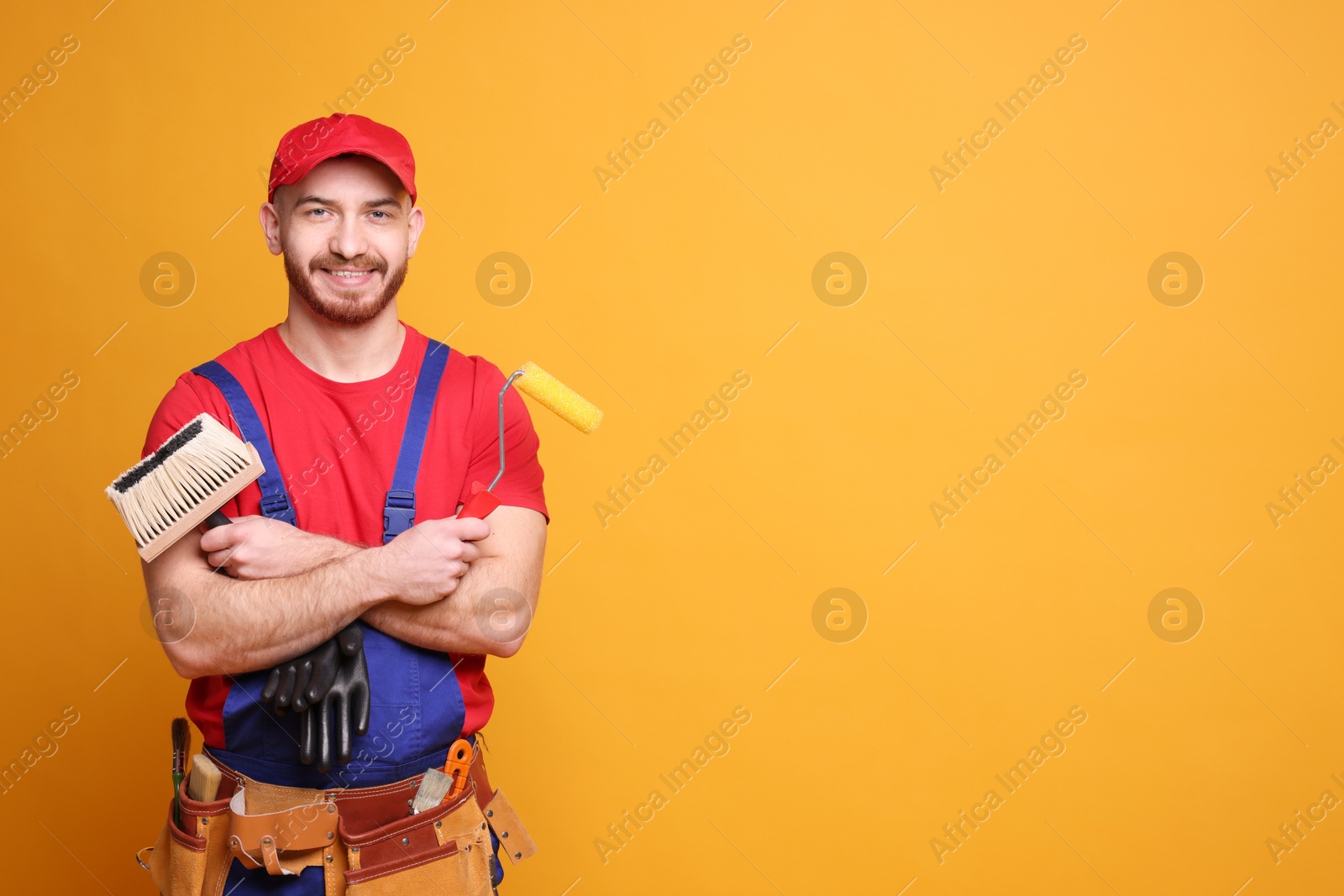 Photo of Professional painter with tools on orange background. Space for text