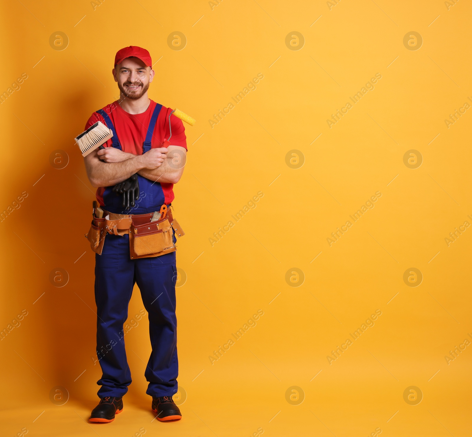 Photo of Professional painter with tools on orange background. Space for text