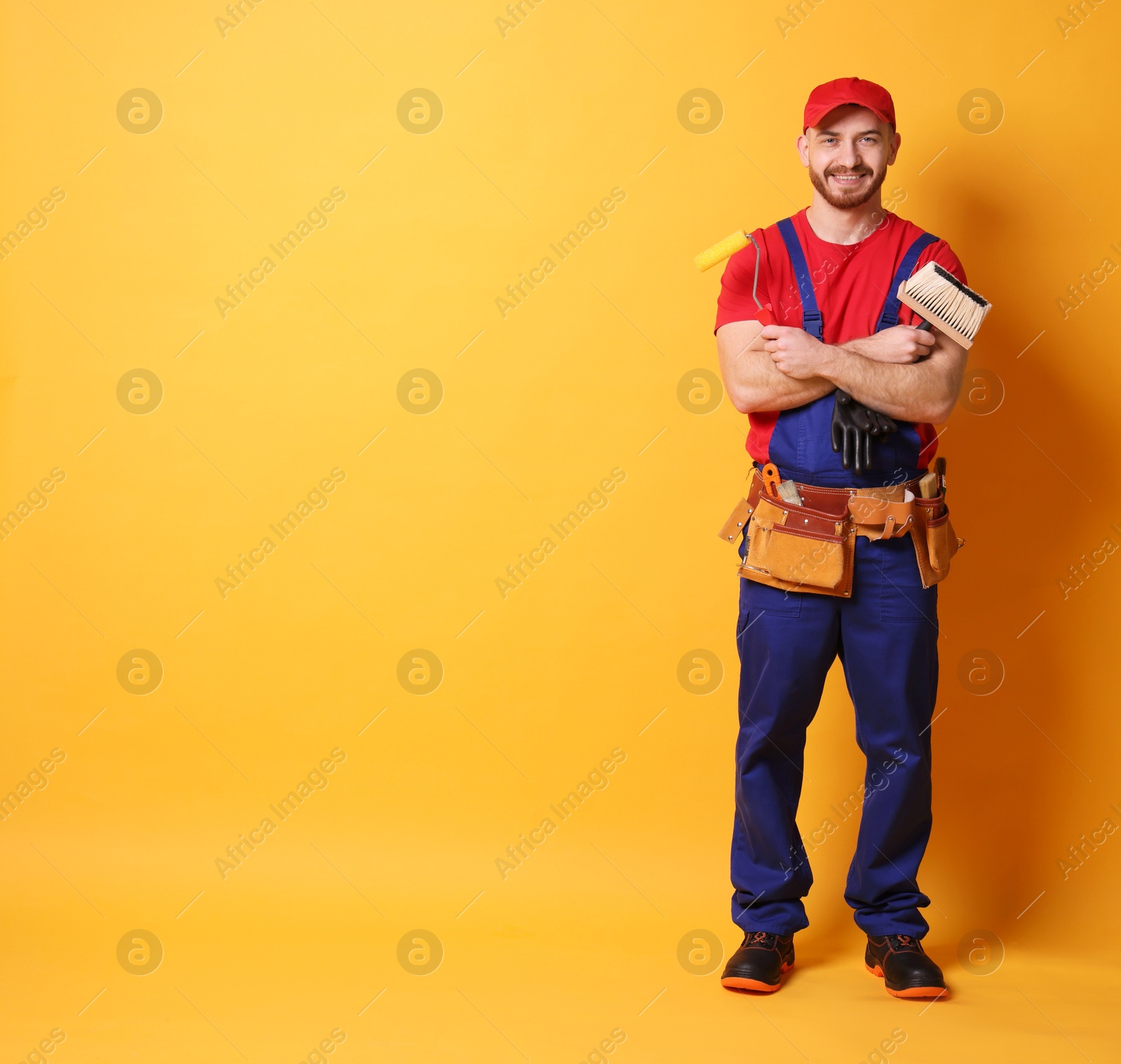 Photo of Professional painter with tools on orange background. Space for text