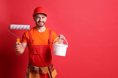 Professional painter with roller and bucket of paint on red background. Space for text