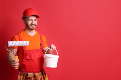 Professional painter with roller and bucket of paint on red background. Space for text