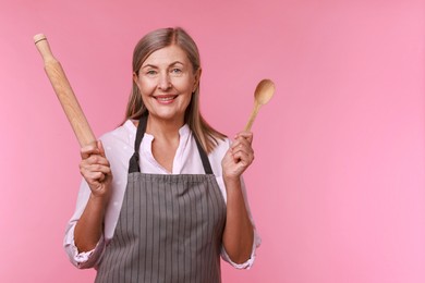 Happy woman with rolling pin and spoon on pink background. Space for text