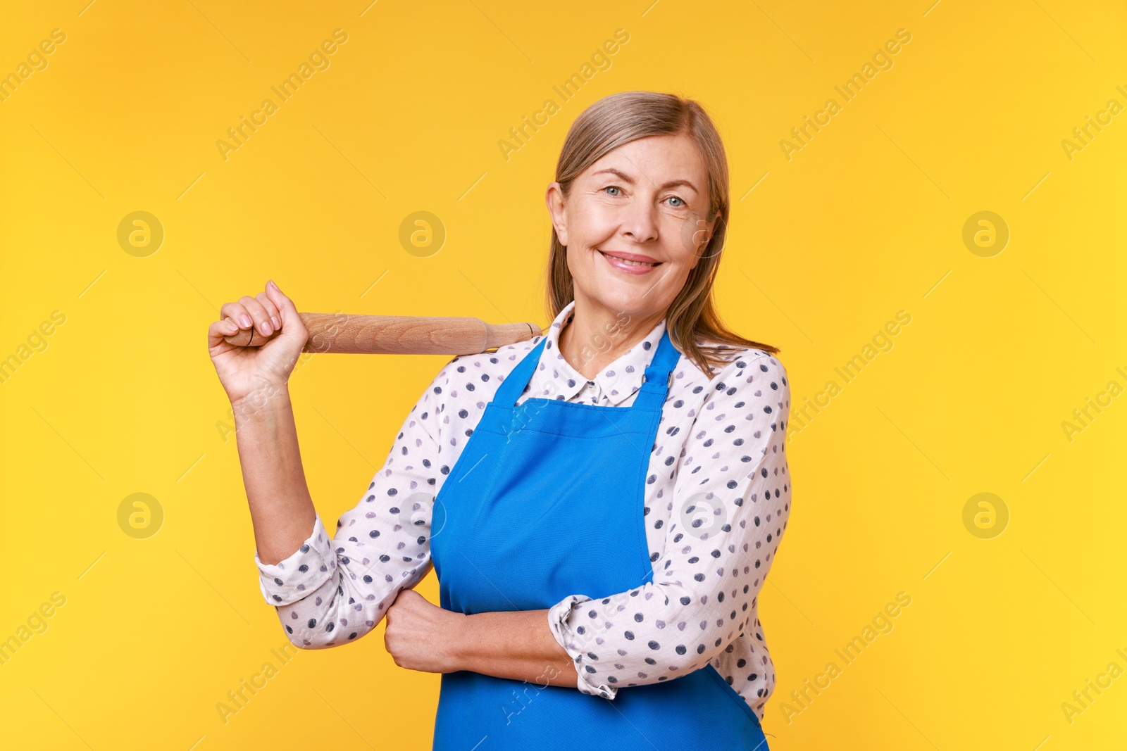 Photo of Happy woman with rolling pin on yellow background