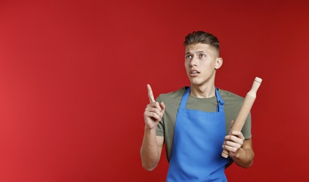 Photo of Man with rolling pin pointing at something on red background