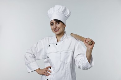 Professional chef with rolling pin on light grey background