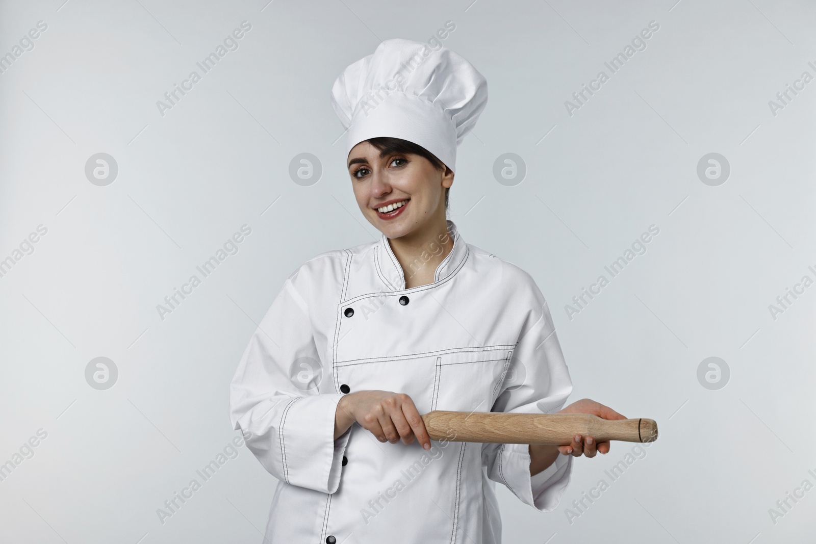 Photo of Professional chef with rolling pin on light grey background