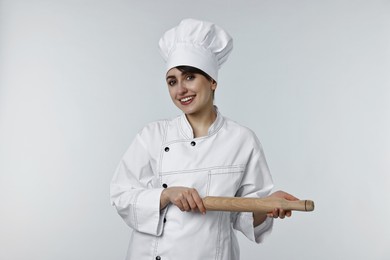 Professional chef with rolling pin on light grey background