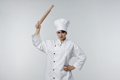 Photo of Angry chef with rolling pin on light grey background