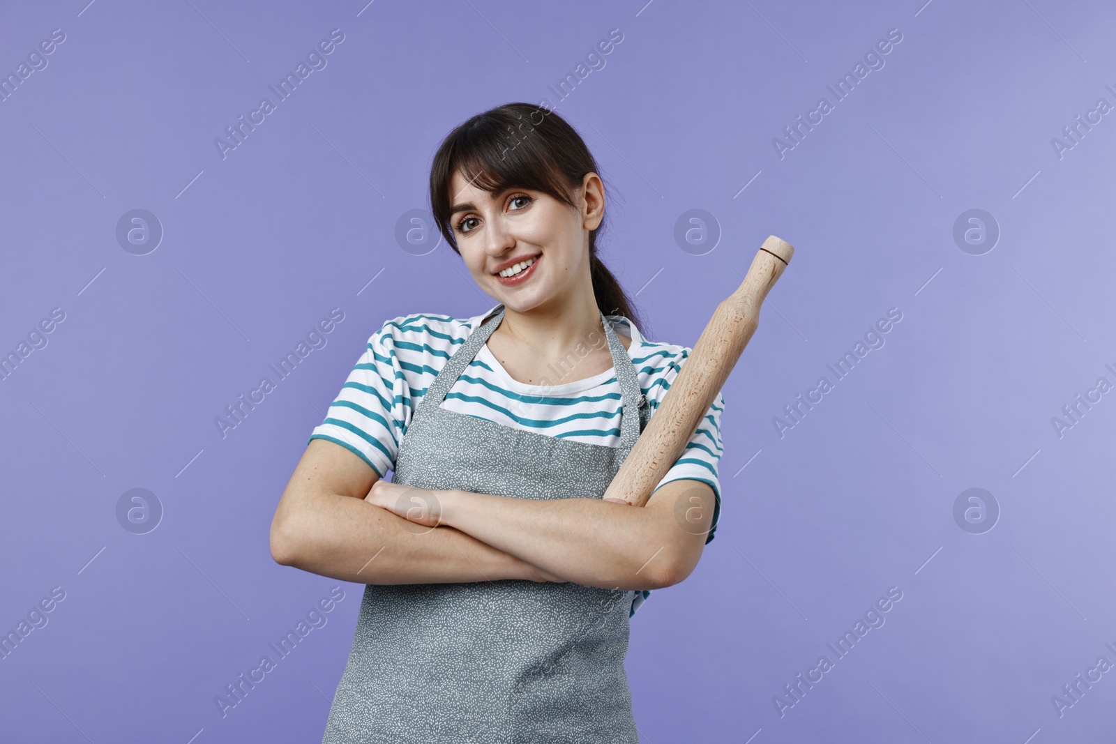 Photo of Happy woman with rolling pin on violet background