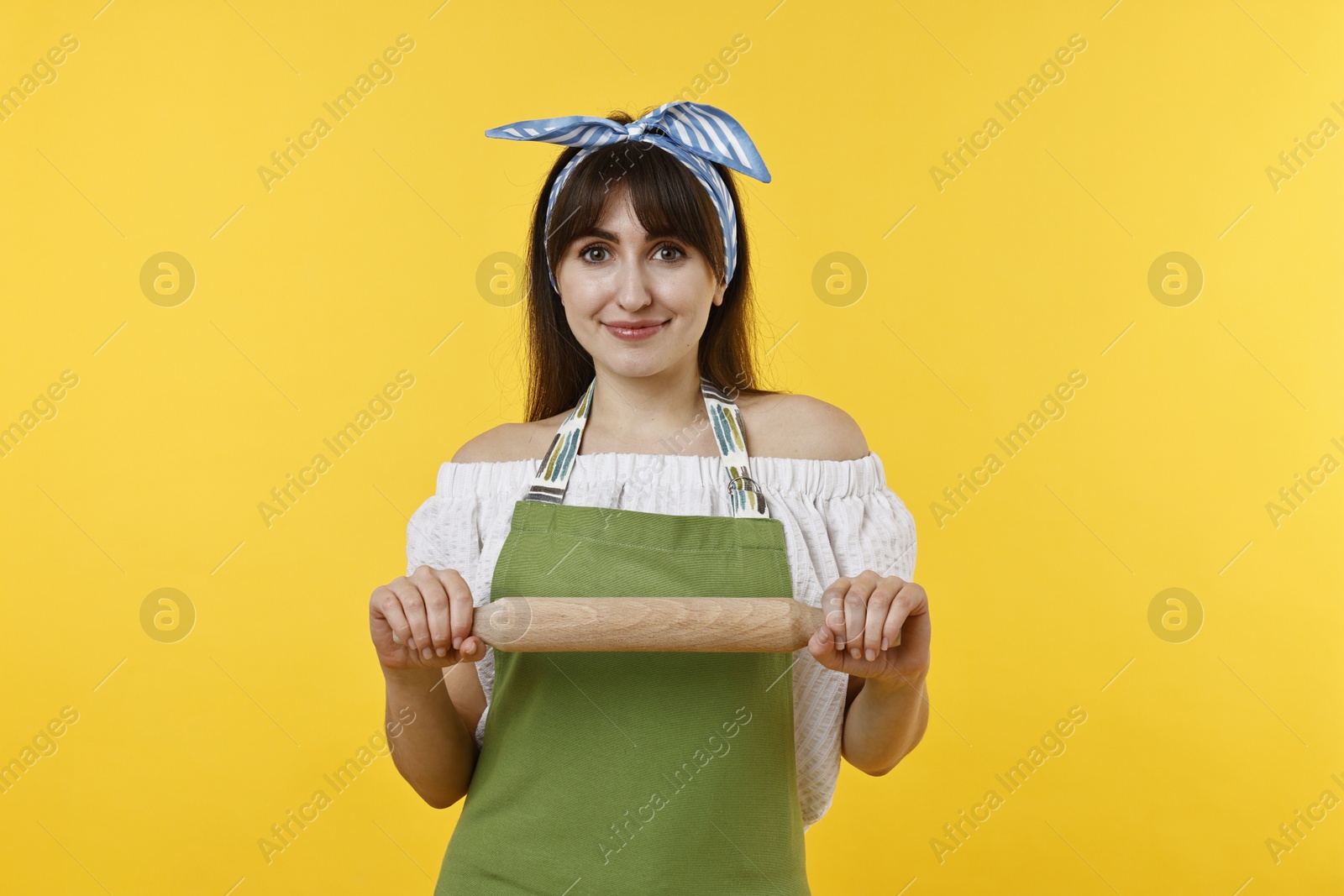 Photo of Happy woman with rolling pin on yellow background