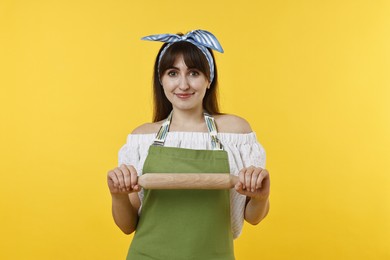 Happy woman with rolling pin on yellow background