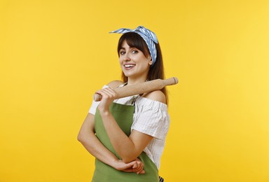 Happy woman with rolling pin on yellow background