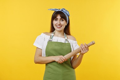 Photo of Happy woman with rolling pin on yellow background