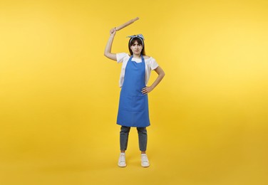 Photo of Angry woman with rolling pin on yellow background