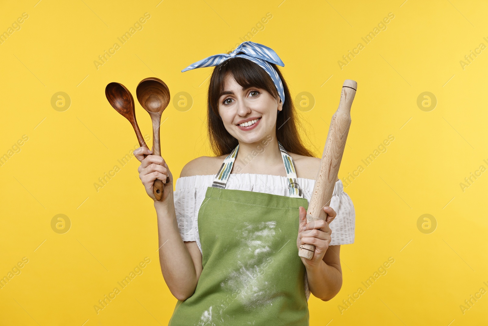 Photo of Happy woman with kitchen utensils on yellow background