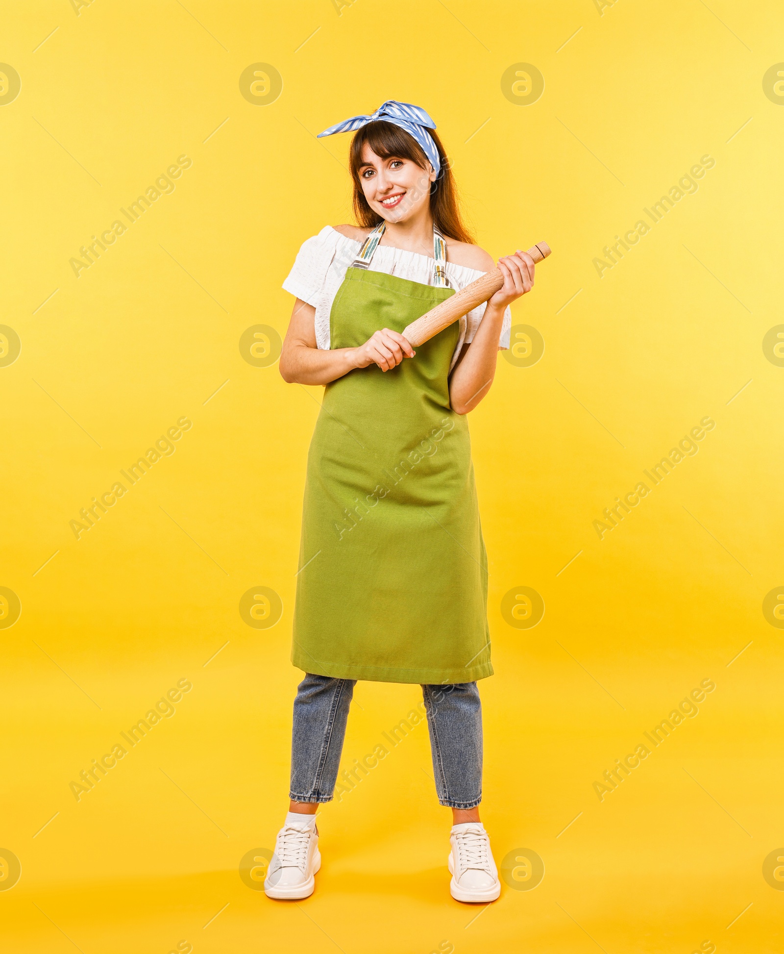 Photo of Happy woman with rolling pin on yellow background