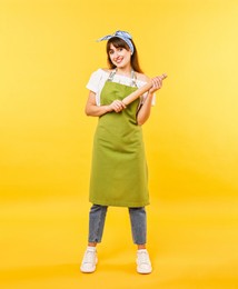 Photo of Happy woman with rolling pin on yellow background