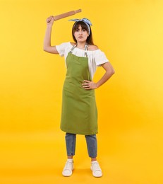 Photo of Angry woman with rolling pin on yellow background