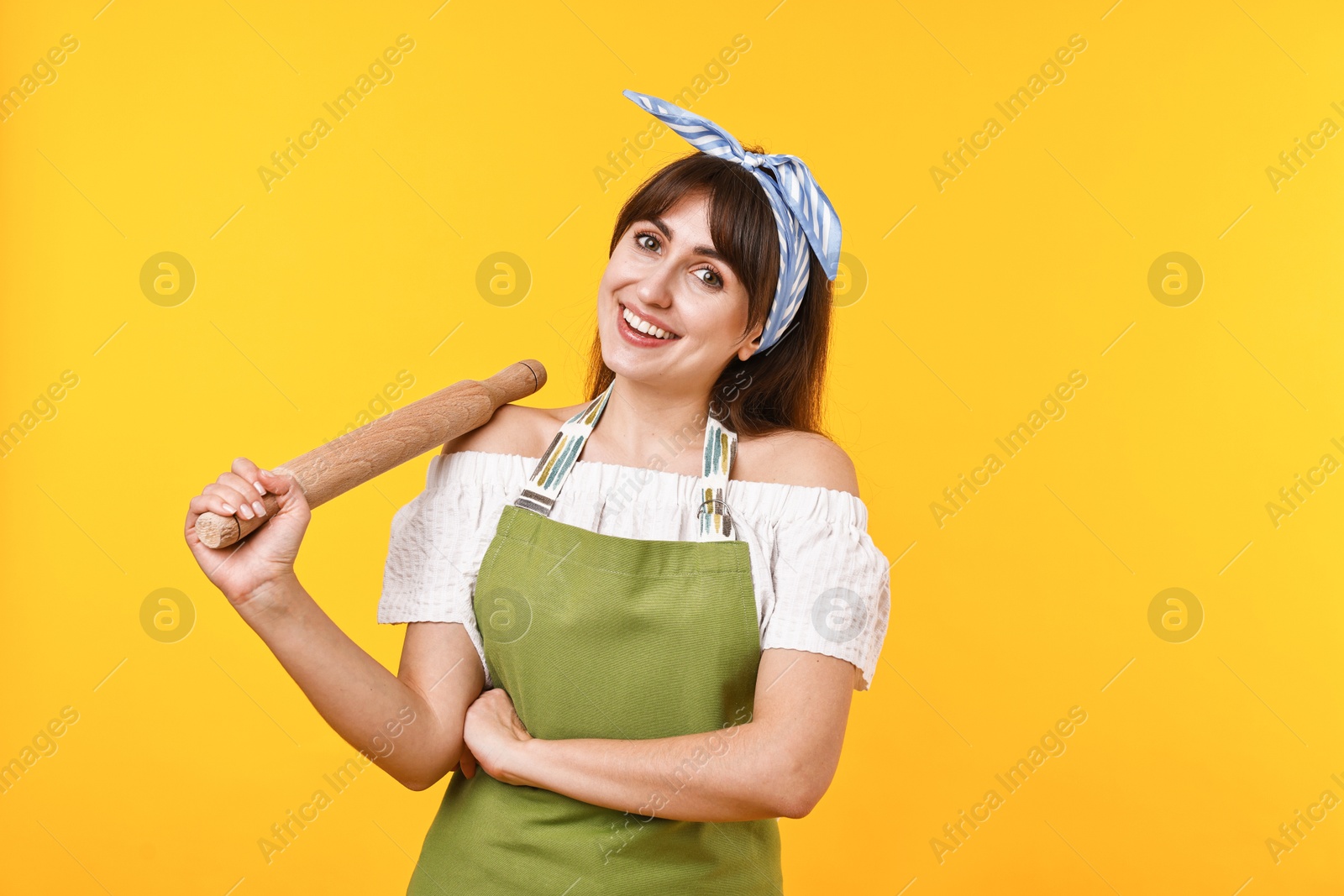 Photo of Happy woman with rolling pin on yellow background