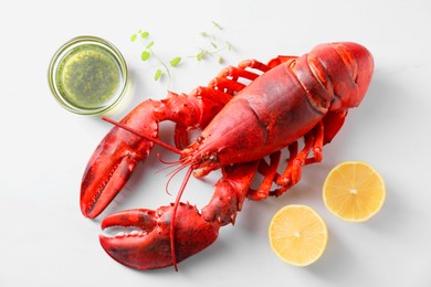 Photo of Delicious boiled lobster with oil, microgreens and lemon pieces on white table, flat lay