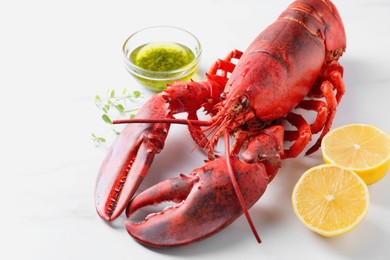 Delicious boiled lobster with oil, microgreens and lemon pieces on white table, closeup