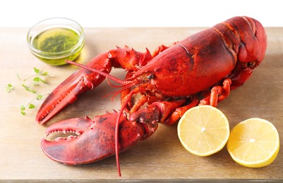 Photo of Delicious boiled lobster with oil, microgreens and lemon pieces on white table, closeup