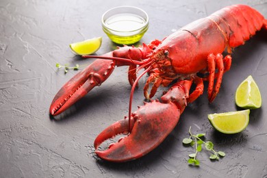 Photo of Delicious boiled lobster with lime pieces, oil and microgreens on black table, closeup