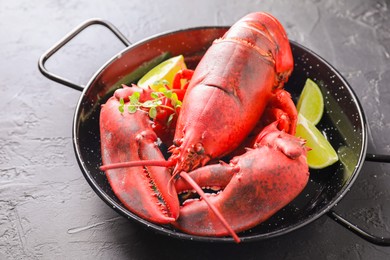 Photo of Delicious boiled lobster with lime pieces and microgreens on black table, closeup