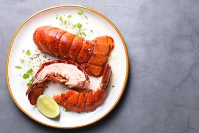 Photo of Delicious tails of boiled lobsters served on grey table, top view. Space for text