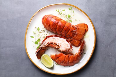 Photo of Delicious tails of boiled lobsters served on grey table, top view