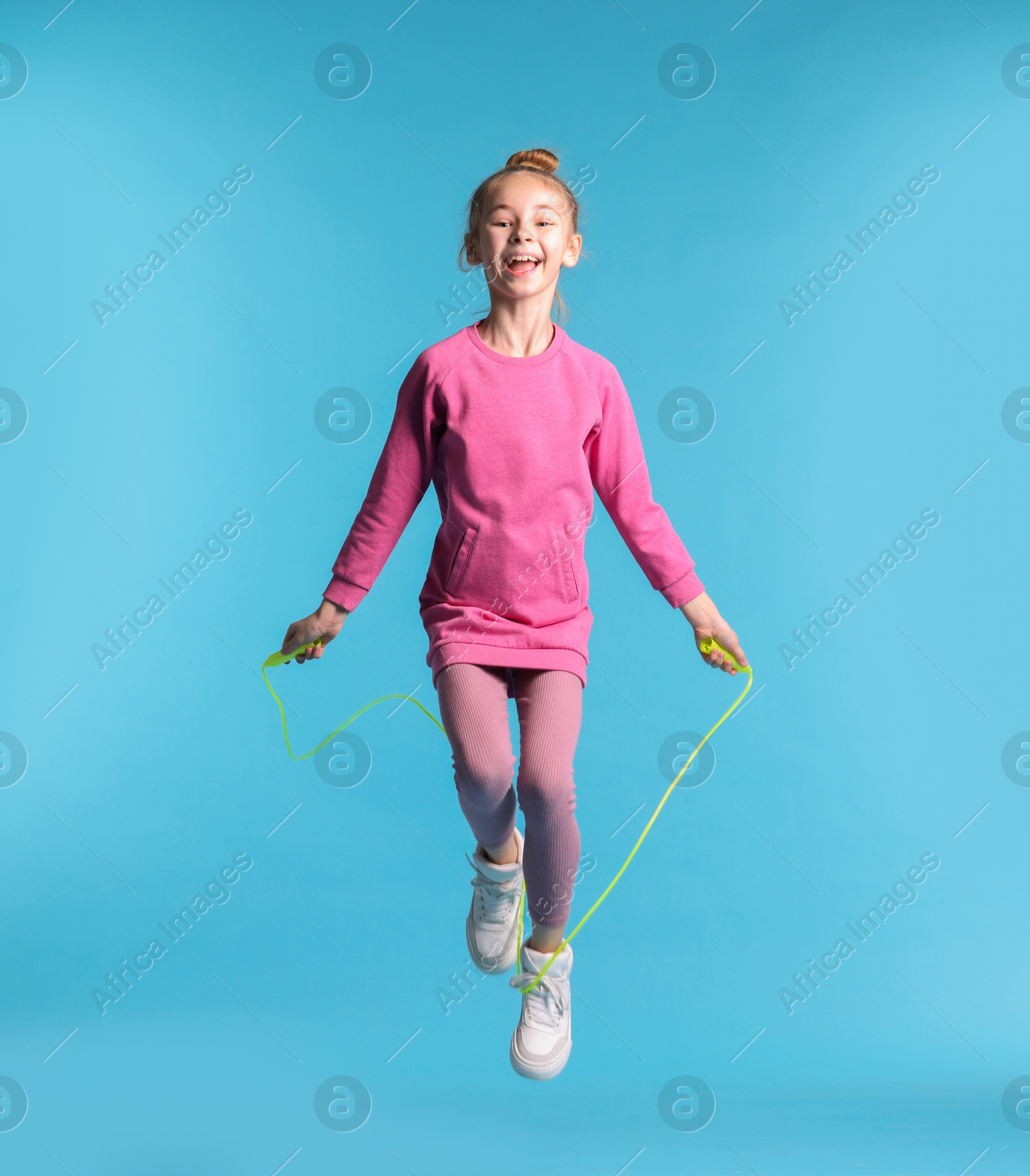 Photo of Cute little girl with jump rope on light blue background