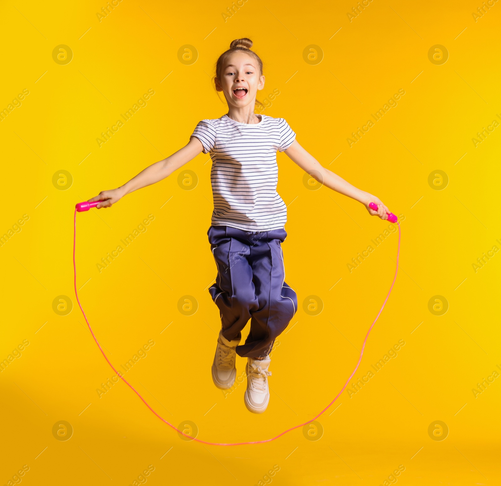 Photo of Cute little girl with jump rope on orange background