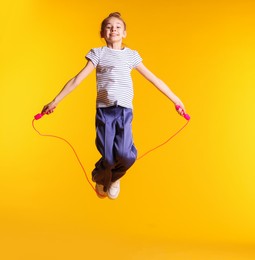 Photo of Cute little girl with jump rope on orange background