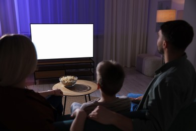 Photo of Happy family watching tv together at home in evening, back view